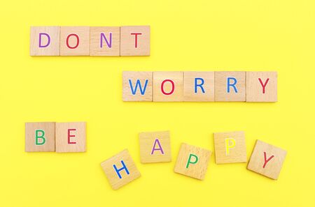 Dont worry be happy, words laid with multi colored letter platelets on a yellow backgroundの写真素材