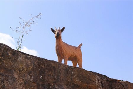 cute figurine of a billygoat standing on an old stone wallの写真素材