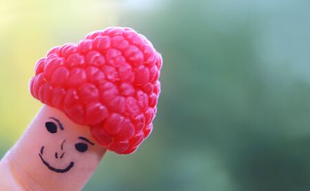 funny finger puppet with raspberry hat in front of a green background with copy spaceの写真素材