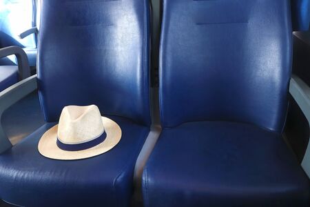 summer vacation, travel by train, symbolic picture with a classic straw hat on blue train seatsの写真素材