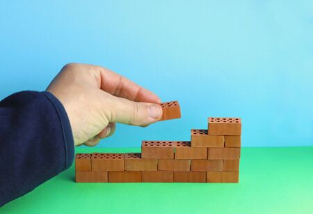 hand building a wall with small brick stonesの写真素材