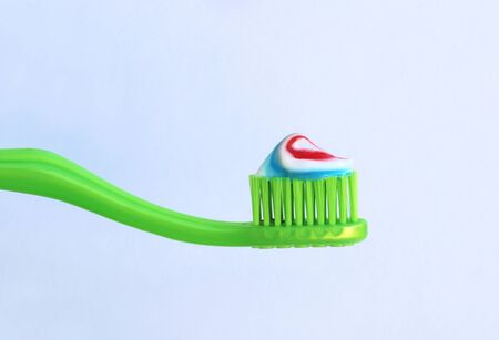 close-up of a green toothbrush with striped toothpaste in front of a gray background with copy spaceの写真素材