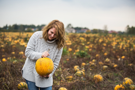 Woman with a pumpkin on a pumpkin fieldの写真素材