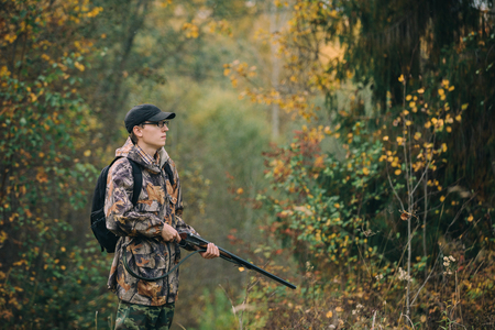 Hunter with hunting rifle in autumn forestの写真素材