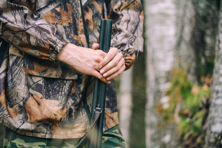 Hunter with hunting rifle in autumn forestの写真素材