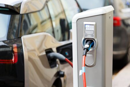 Close up of charging station. A cable is connected to the station, which charges an electric car