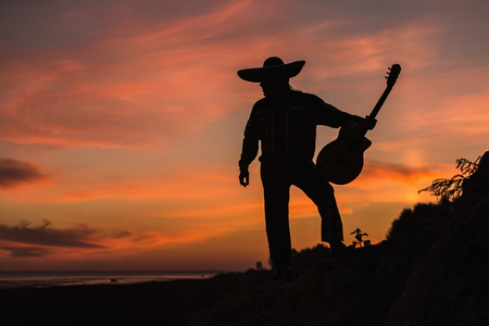 Mexican musician mariachi with a guitar. Silhouette on sunset backgroundの写真素材