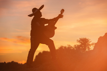 Mexican musician mariachi with a guitar. Silhouette on sunset backgroundの写真素材
