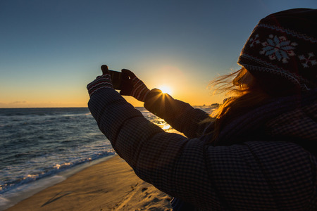 Woman takes a picture on phone. South Korea, Gangneung, coast of Japan sea.の写真素材