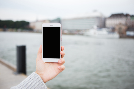 Hand with phone on a background of european cityの写真素材