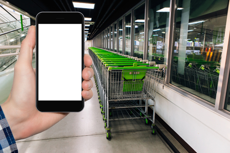 A man's hand with a smartphone on the background of the shopping center's interior. In a blank screen you can write information.の写真素材