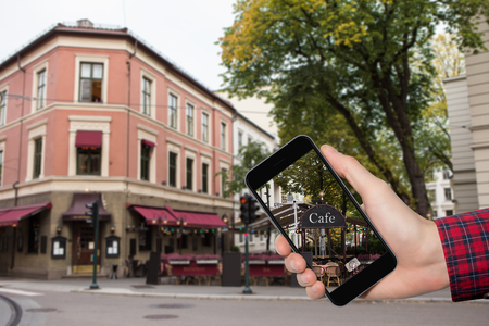 Man's hand with a phone on a background of city streets in Europe.の写真素材
