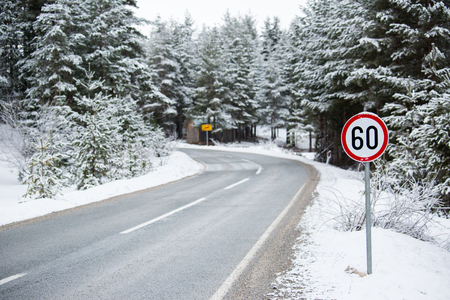 Mountain winter road with a speed limit signの写真素材