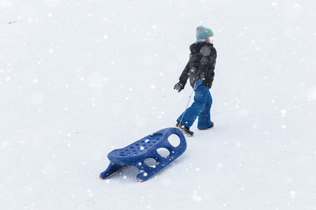 A child with a sled in a ski resortの写真素材