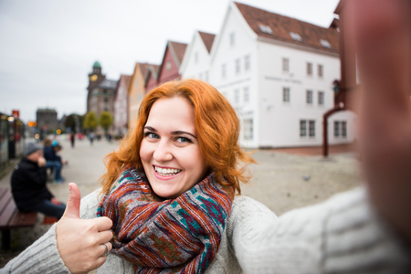 Red-haired girl is photographed on a background of colorful houses in Europe.の写真素材