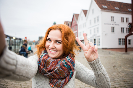 Red-haired girl is photographed on a background of colorful houses in Europe.の写真素材