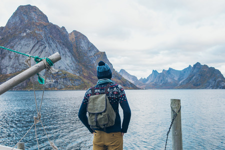 Traveler looking at the mountains, standing on a wooden pier
