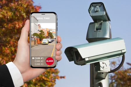 Hand with phone. On the screen interface of remote control surveillance camera