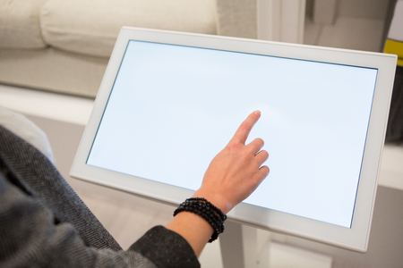 A woman touching the screen of self service device in the store.