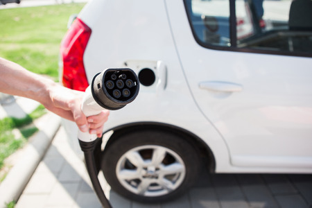 A man holds a charger plug for an electric car.の写真素材