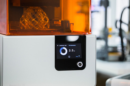 A stereolithography 3d printer in the laboratory prints a structure from a photopolymer.  On the display the process indicator and the number of layers. Creating scaled model by UV polymerization.の写真素材