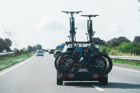 Car with bikes on the hitch-mounting bike rack on the highwayの写真素材