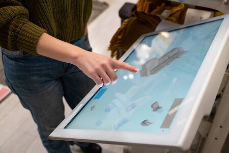 Woman with phone configuring furniture at the self-service desk in the storeの写真素材