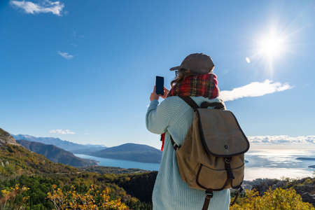 Traveler with a backpack and a smartphone stands on a mountain