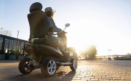 Woman tourist riding a four wheel mobility electric scooter on a city street.の写真素材
