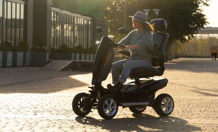 Woman tourist riding a four wheel mobility electric scooter on a city street.の写真素材