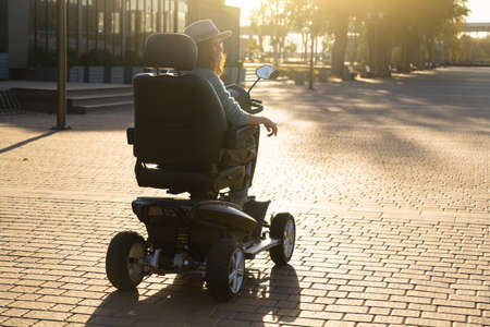 Woman tourist riding a four wheel mobility electric scooter on a city street.