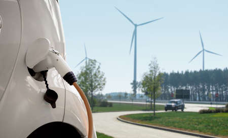 Electric car with charging plug on a background of wind turbinesの写真素材