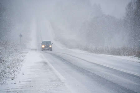 The car is driving on a winter road in a blizzardの写真素材