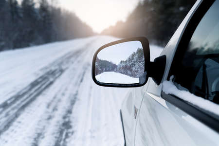 White car on a winter road through a snow covered forest.の写真素材