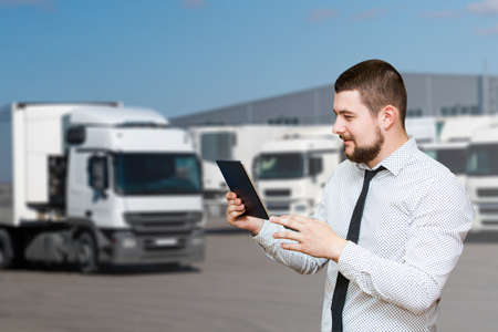 Manager with a digital tablet on the background of trucks. Fleet managementの写真素材