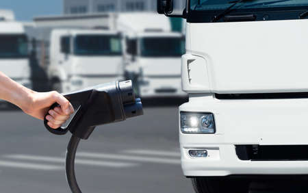 Hand with charging plug on a background of electric truckの写真素材