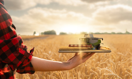 Farmer holding a tablet with a combine harvester. Digital transformation in agriculture. smart farming conceptの写真素材