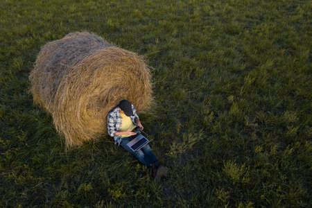 Farmer with laptop on the field. Drone point of view.の写真素材