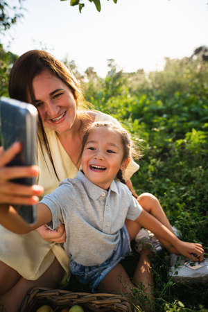 Caucasian mother and her Asian daughter take a selfieの写真素材