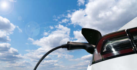 Close up of electric car with a charging station on a background of blue skyの写真素材