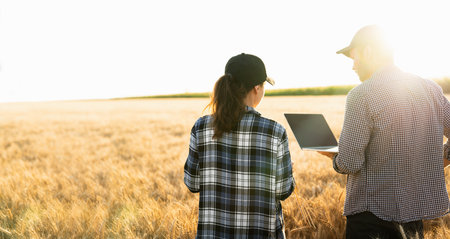 Couple of farmers examines the field of cereals and sends data to the cloud from the digital tablet and laptop. Smart farmingの写真素材