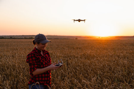 Farmer controls drone sprayer with a tablet on a sunset. Smart farming and precision agricultureの写真素材