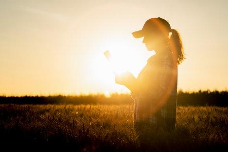 Farmer examines the field of cereals and sends data to the cloud from the tablet. Smart farming and digital agriculture.の写真素材