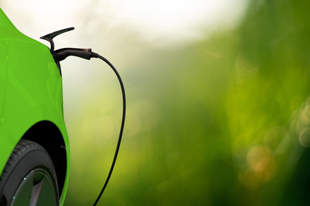 Close up of electric car inlet with a connected charging cable on a green backgroundの写真素材