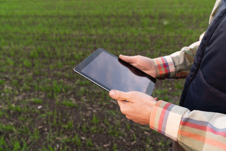 Farmer with digital tablet on an agricultural field. Close up. Smart farming and digital agricultureの写真素材