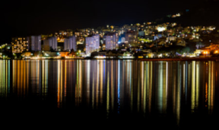Blurred view of night city with reflection in water.