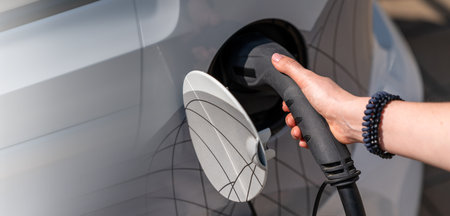 Woman holding plug of electric car charging station