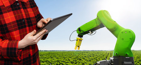 Farmer controls robotic arm with a tablet. Smart farming and digital transformation in agriculture. High quality photoの写真素材