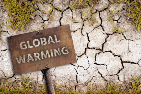Rusty sign with text GLOBAL WARMING on a background of dry cracked soil. Climate change concept. High quality photoの写真素材