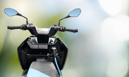 Electric scooter with connected charging cable on a green background. High quality photoの写真素材